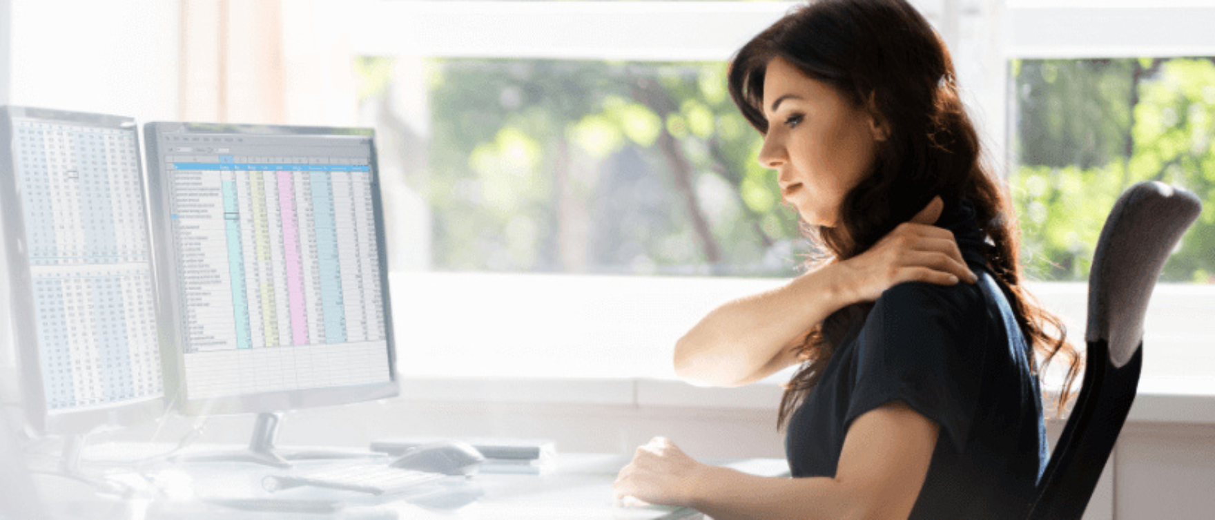 Woman experiencing neck pain while working at a desk, indicating inflammation issues.