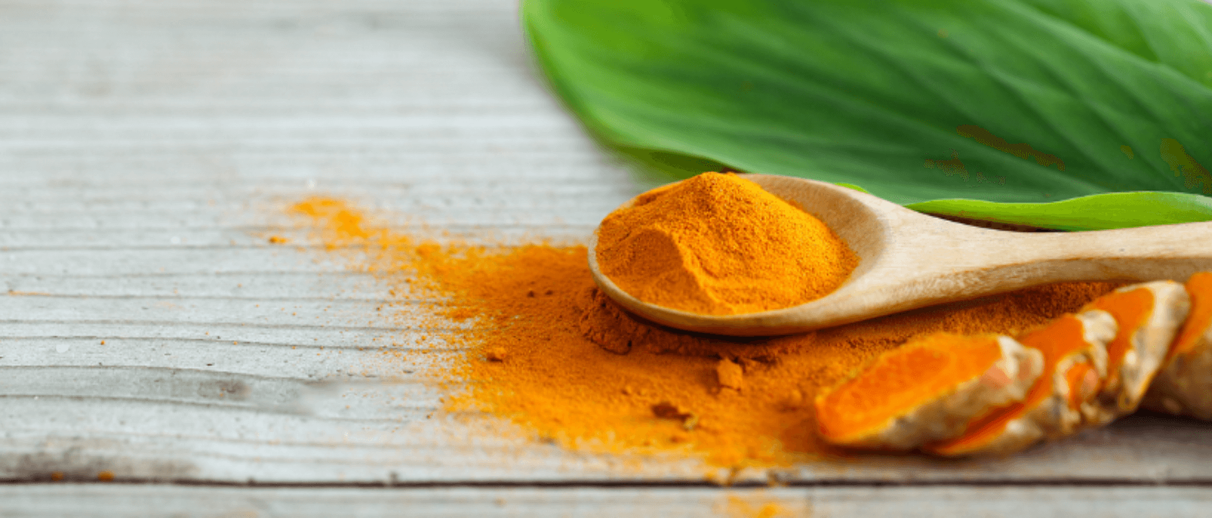 Turmeric powder and capsules displayed on a wooden surface, highlighting anti-inflammatory benefits.