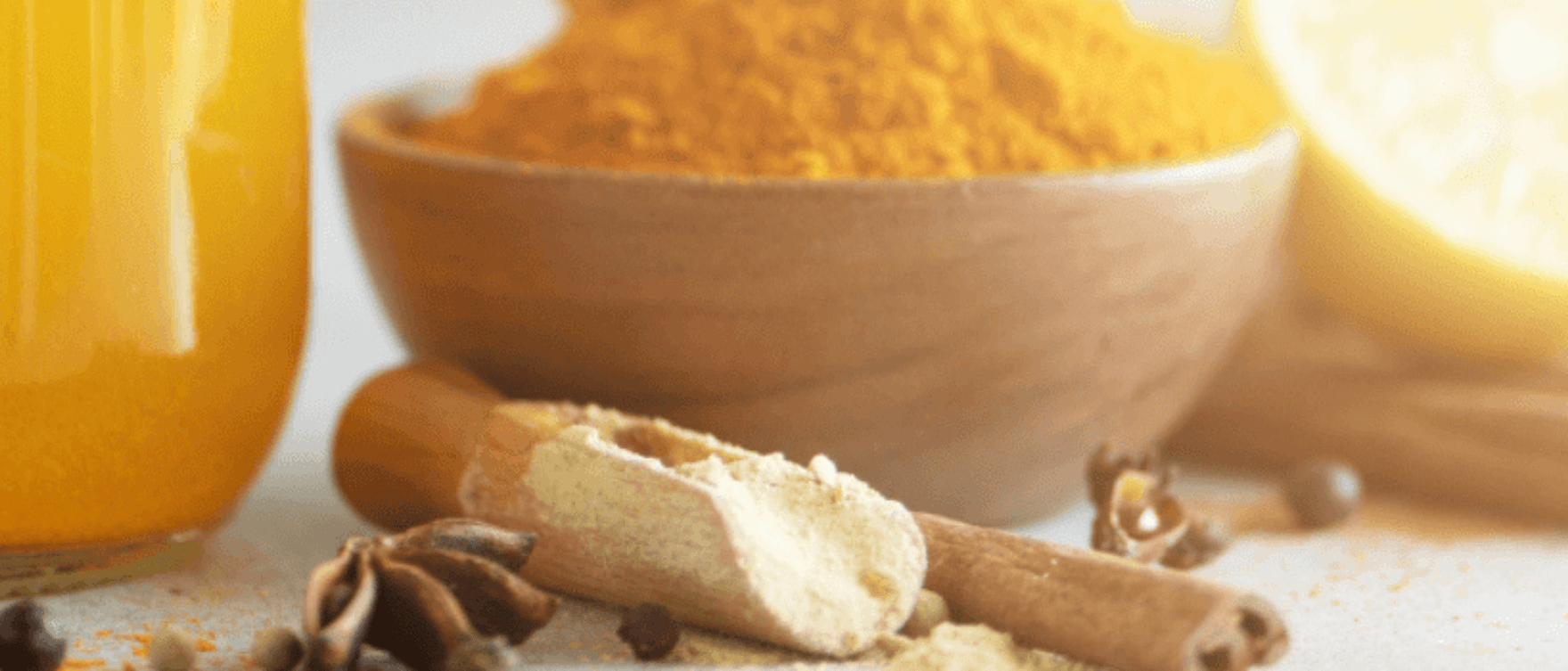 A bowl of turmeric powder with a wooden spoon, surrounded by spices like cinnamon and cloves, symbolizing turmeric’s natural stress-relief benefits.