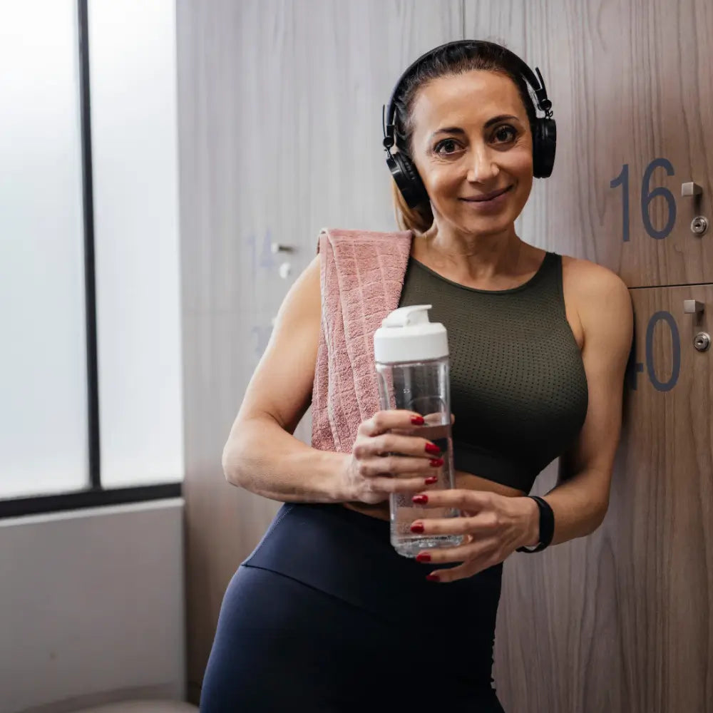 Woman standing with water bottle at the gym